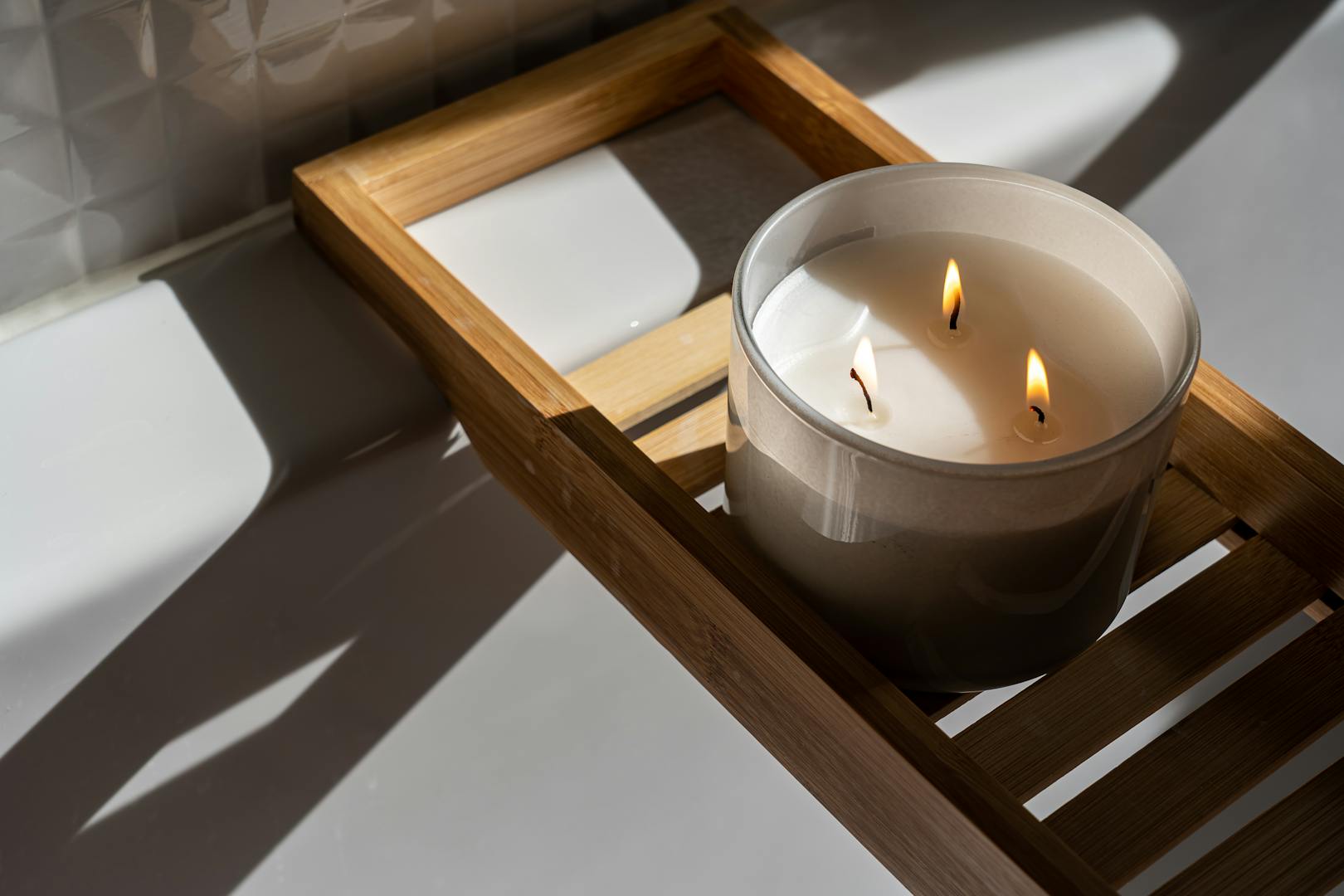 Un décor minimaliste avec une bougie allumée sur un plateau en bois, projetant des ombres chaudes et créant une ambiance apaisante.