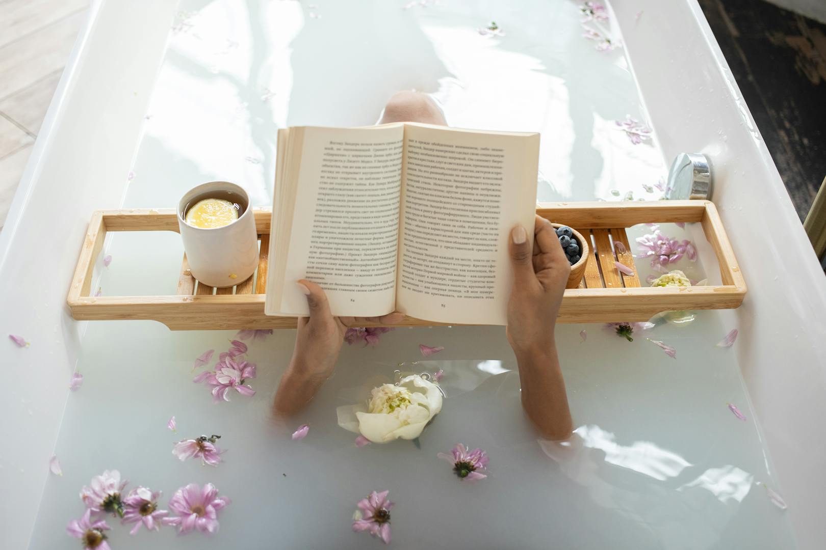 Profitez d'un bain tranquille avec un livre entouré de fleurs et de thé chaud. Cadre idéal pour une journée au spa.