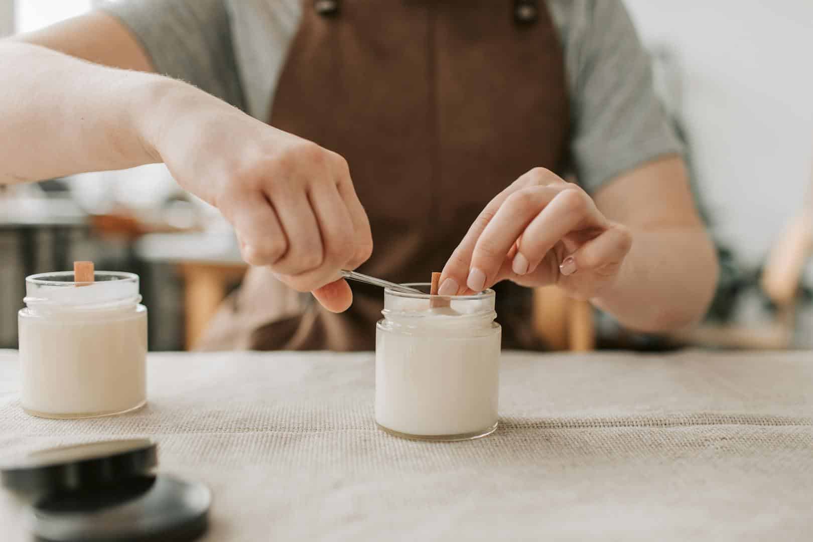 Gros plan de bougies artisanales fabriquées à la main avec des mèches en bois en atelier.